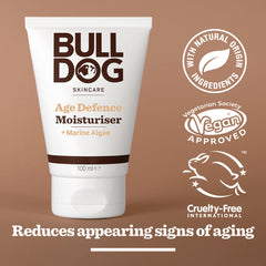 A white tube of Age Defence Moisturiser is shown, featuring logos for natural origin ingredients, vegan approved, and cruelty-free. Text below states: “Reduces appearing signs of aging.”.